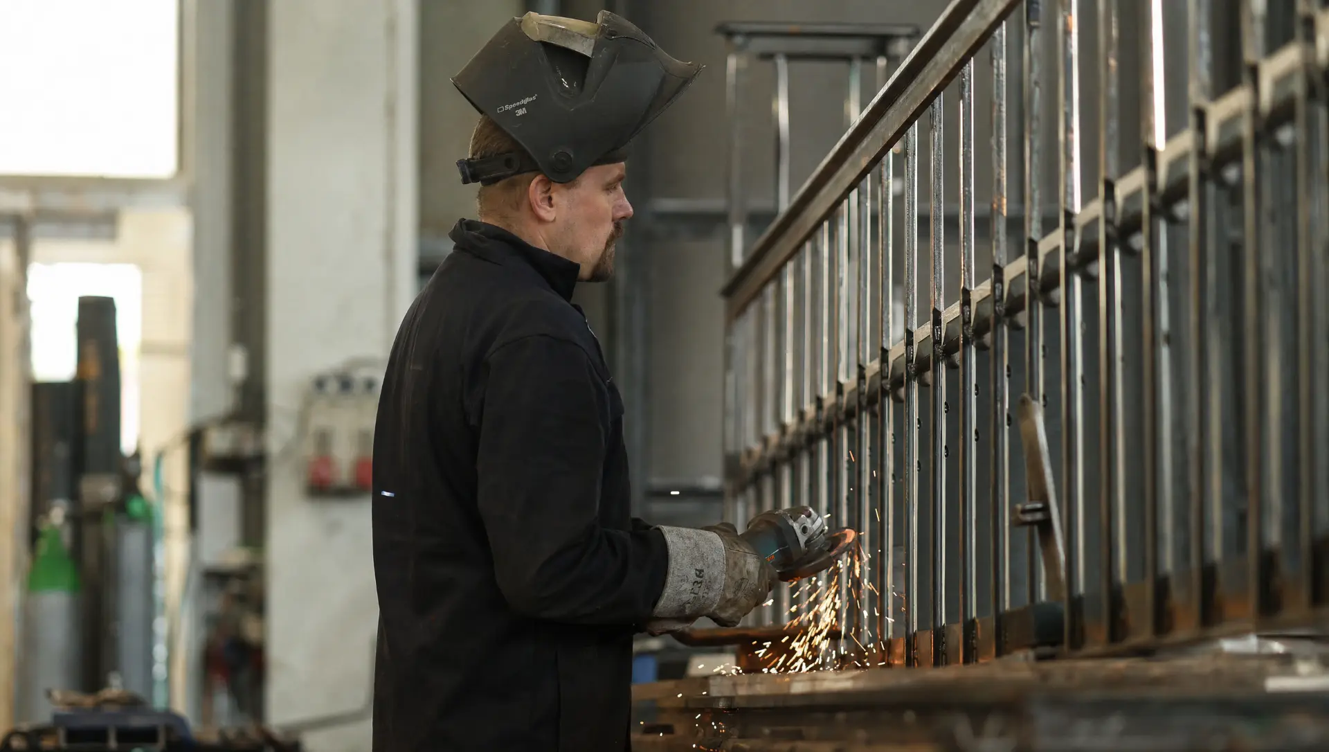 Metallbauer in Profilansicht mit Schweißmaske am Geländer